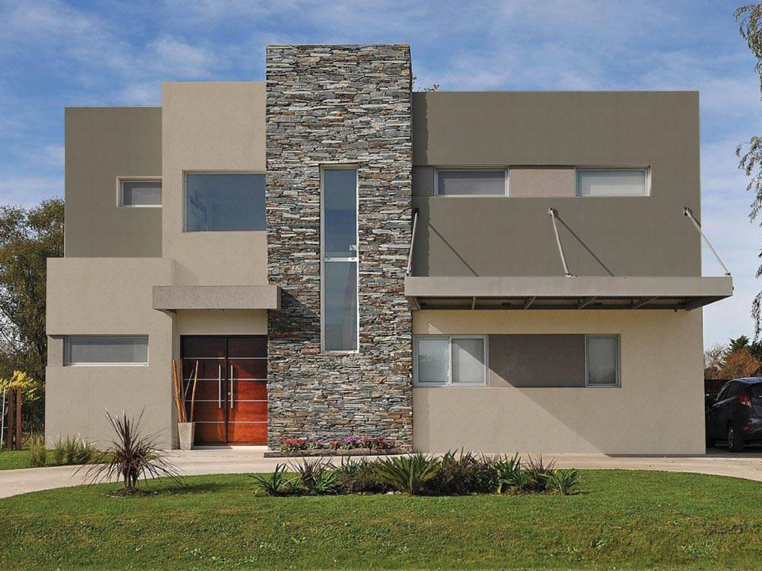 Fachada de vivienda moderna con revestimiento texturado Revear en tonos neutros y muro central de piedra natural, combinando materiales y líneas geométricas.