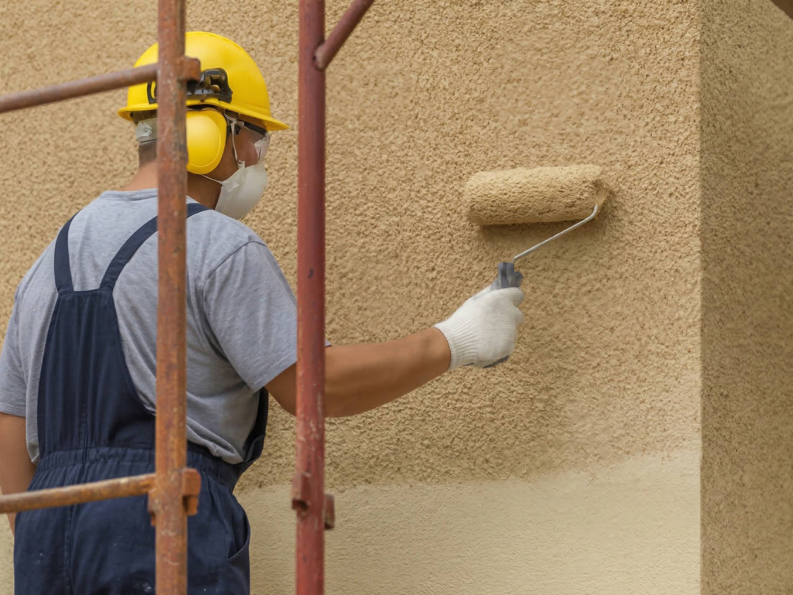 aplicador de revestimiento texturado aplicando revestimiento revear beige con rodillo en pared exterior