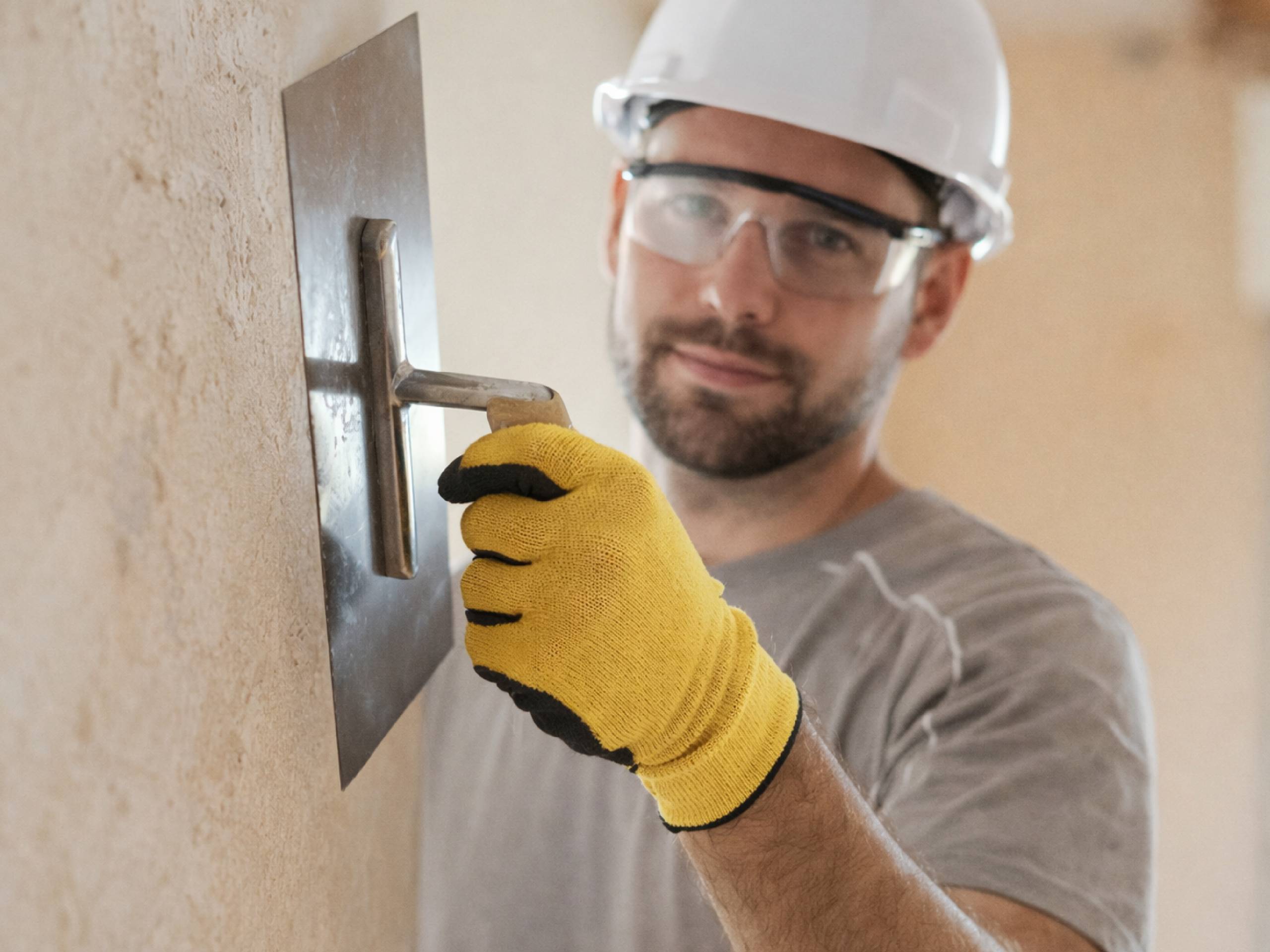 Trabajador de la construcción aplicando revestimientos texturados Revear sobre pared interior